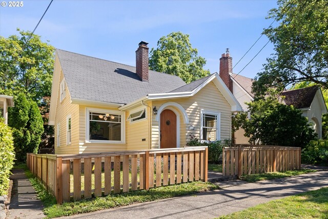 view of front of property with a chimney, roof with shingles, and a fenced front yard