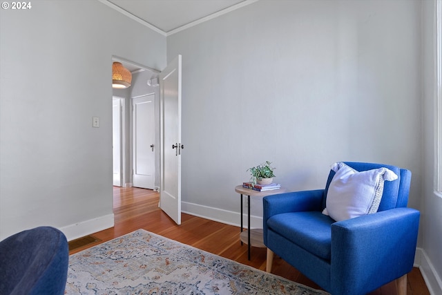 living area featuring visible vents, wood finished floors, baseboards, and ornamental molding
