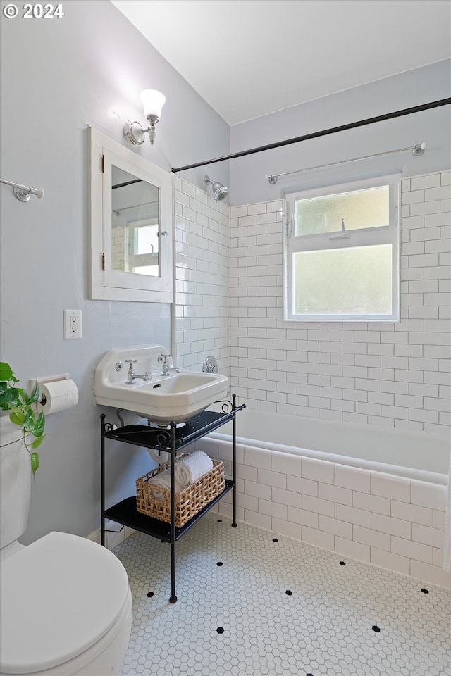 bathroom featuring tile patterned floors, a sink, tiled shower / bath, and toilet