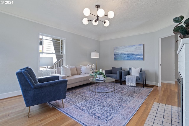 living area with a textured ceiling, baseboards, a notable chandelier, wood finished floors, and ornamental molding