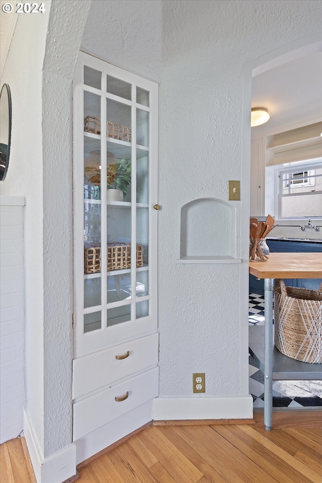 interior details featuring a textured wall, baseboards, and wood finished floors