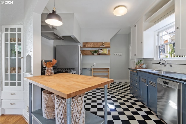 kitchen with light floors, blue cabinets, appliances with stainless steel finishes, and a sink