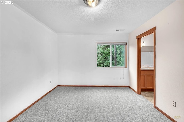 empty room featuring light carpet, baseboards, visible vents, and a textured ceiling