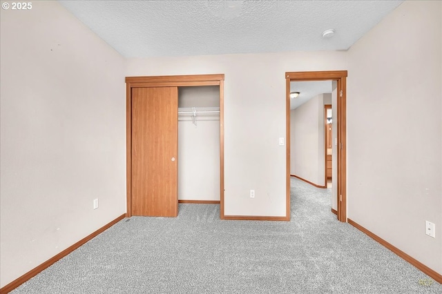 unfurnished bedroom featuring light carpet, a closet, baseboards, and a textured ceiling