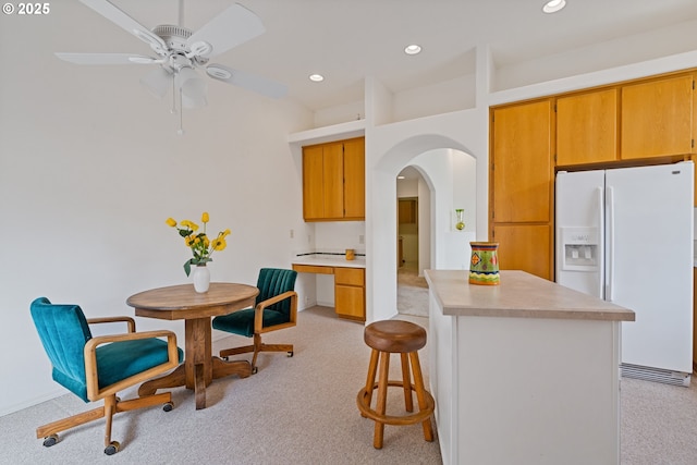 1939 NE Harewood Pl, Hillsboro, OR 97124 - kitchen with white fridge with ice dispenser, arched walkways, light colored carpet, light countertops, and a ceiling fan