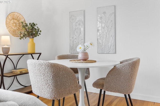 dining space with baseboards and wood finished floors