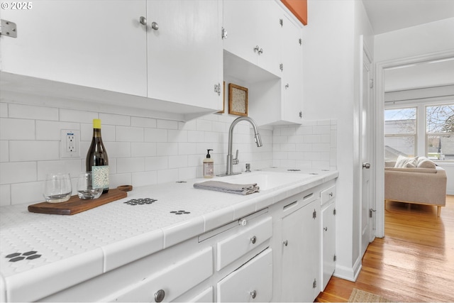 kitchen with light wood finished floors, white cabinets, and a sink