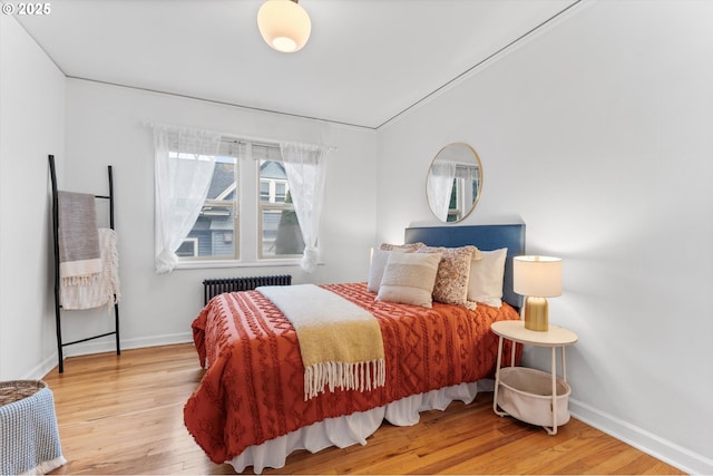 bedroom featuring radiator heating unit, baseboards, and wood finished floors