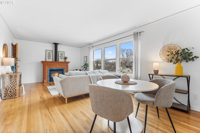 dining space with light wood-style floors, baseboards, and a glass covered fireplace