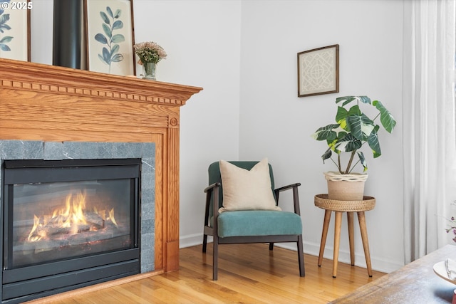 living area featuring a tiled fireplace, wood finished floors, and baseboards