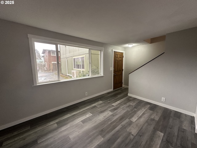 empty room with dark wood-style flooring and baseboards