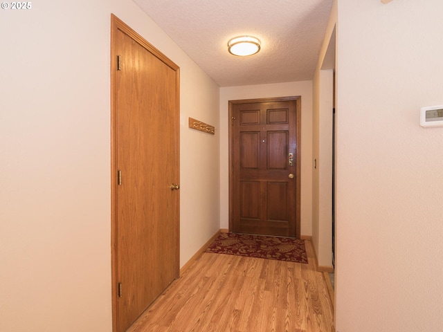 corridor featuring light hardwood / wood-style flooring and a textured ceiling