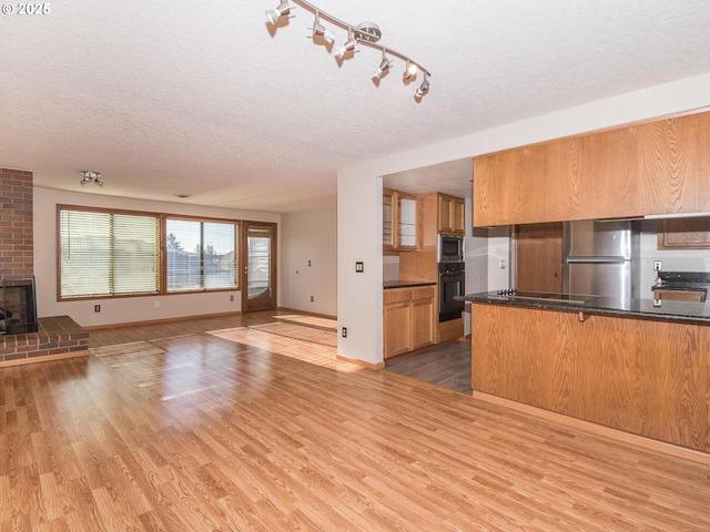 kitchen featuring kitchen peninsula, a textured ceiling, stainless steel appliances, and light hardwood / wood-style flooring