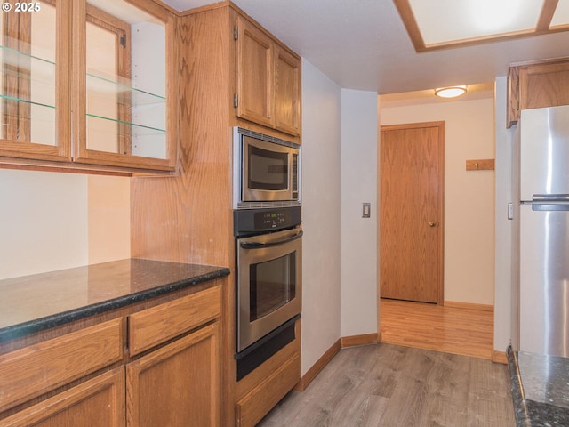 kitchen featuring dark stone counters, light hardwood / wood-style flooring, and stainless steel appliances