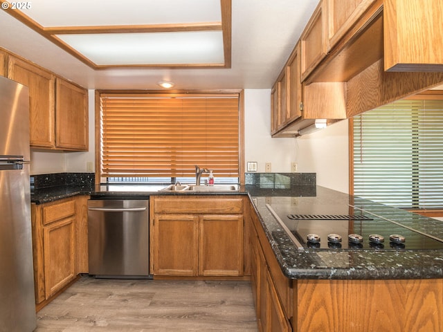 kitchen with custom exhaust hood, dark stone counters, sink, light wood-type flooring, and stainless steel appliances