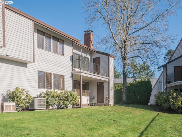 back of house featuring a yard, a balcony, and central air condition unit