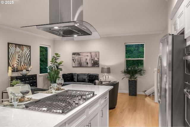 kitchen featuring ornamental molding, white cabinets, light wood finished floors, stainless steel appliances, and baseboards