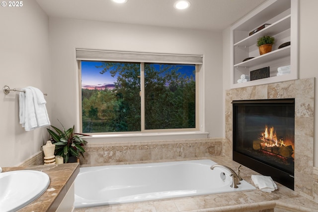 bathroom featuring a bath, a fireplace, recessed lighting, and vanity