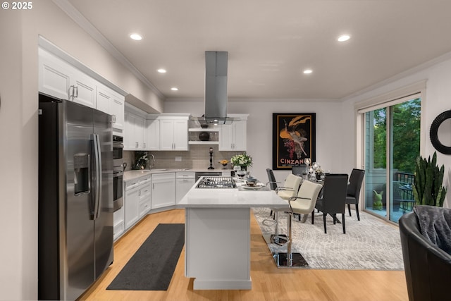 kitchen featuring appliances with stainless steel finishes, crown molding, light countertops, a kitchen island, and light wood-style flooring
