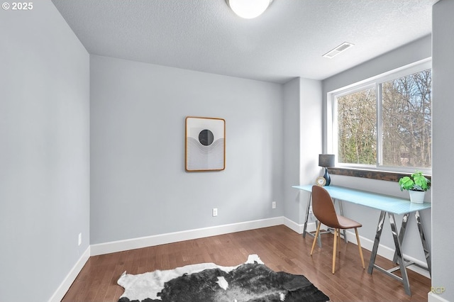 home office featuring baseboards, a textured ceiling, visible vents, and wood finished floors