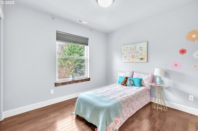 bedroom featuring visible vents, baseboards, and wood finished floors