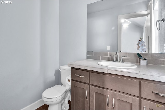 half bath featuring toilet, baseboards, and vanity