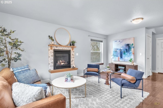 sitting room featuring a tile fireplace, baseboards, and wood finished floors