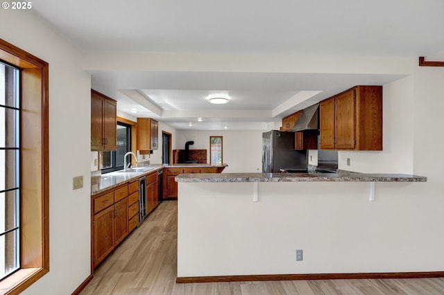 915 Marquet Way, Eugene, OR 97401 - kitchen with a peninsula, a tray ceiling, light wood-style flooring, a sink, and freestanding refrigerator