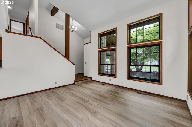 915 Marquet Way, Eugene, OR 97401 - unfurnished living room featuring wood finished floors, stairs, high vaulted ceiling, baseboards, and a chandelier