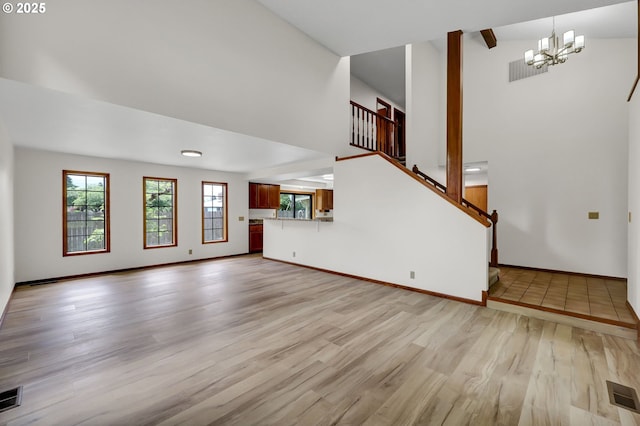 915 Marquet Way, Eugene, OR 97401 - unfurnished living room with light wood finished floors, a chandelier, high vaulted ceiling, stairs, and baseboards