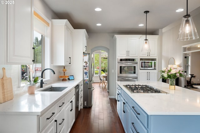14925 SE Pebble Beach Dr, Happy Valley, OR 97086 - kitchen with stainless steel appliances, arched walkways, a sink, white cabinets, and recessed lighting