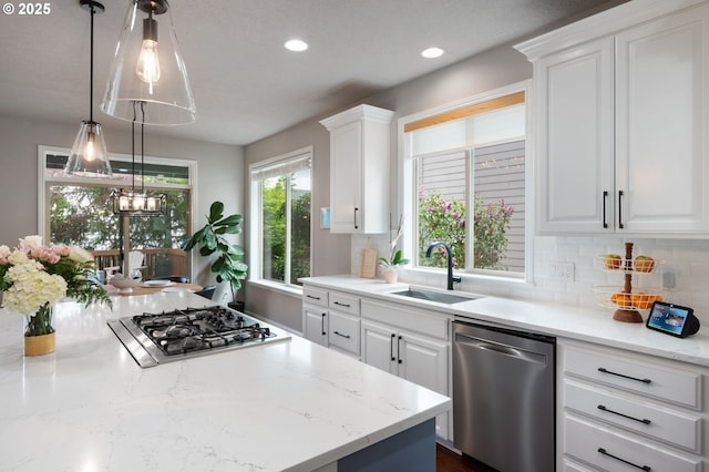 14925 SE Pebble Beach Dr, Happy Valley, OR 97086 - kitchen with appliances with stainless steel finishes, a sink, backsplash, white cabinetry, and decorative light fixtures