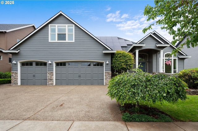 14925 SE Pebble Beach Dr, Happy Valley, OR 97086 - view of front of house featuring stone siding, roof mounted solar panels, concrete driveway, and an attached garage