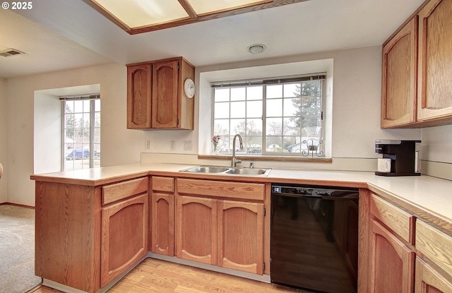 kitchen with visible vents, a sink, black dishwasher, a peninsula, and light countertops