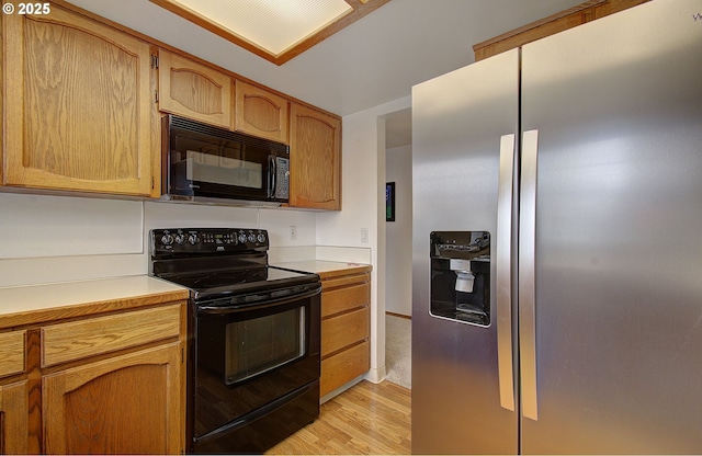 kitchen featuring black appliances, light wood-style flooring, and light countertops