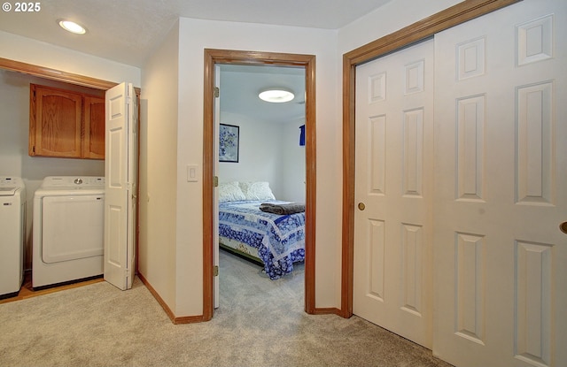 hallway with baseboards, light carpet, and washing machine and dryer