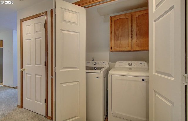 clothes washing area featuring washing machine and dryer, cabinet space, and light carpet