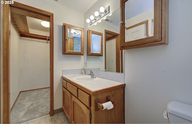 bathroom featuring visible vents, toilet, vanity, and baseboards