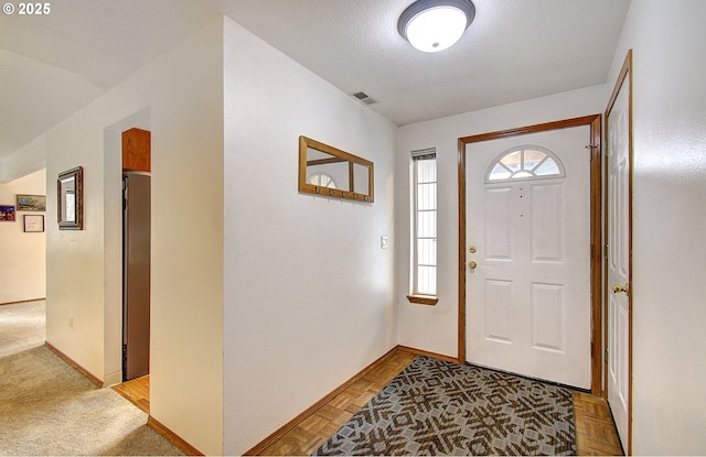 foyer with visible vents, baseboards, and a textured ceiling