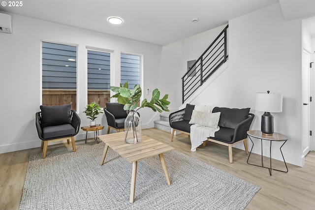 living area with a wall mounted AC and light wood-type flooring