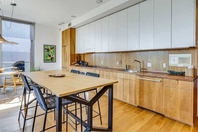 2530 SE 26th Ave Unit 401, Portland, OR 97202 - kitchen with a sink, light wood-style flooring, appliances with stainless steel finishes, modern cabinets, and pendant lighting