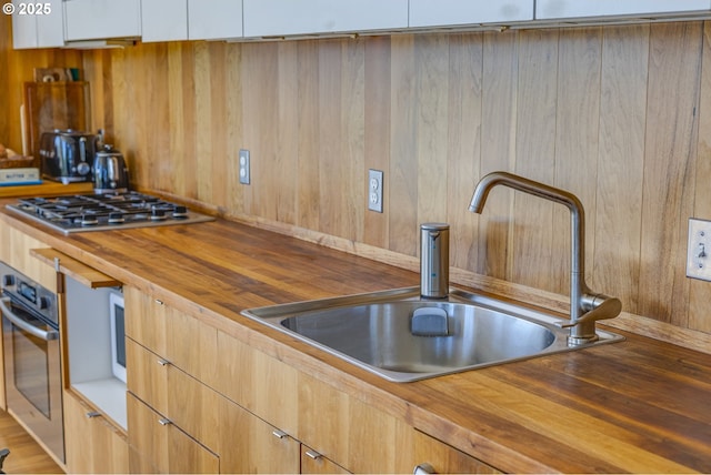 2530 SE 26th Ave Unit 401, Portland, OR 97202 - kitchen with butcher block counters, a sink, stainless steel appliances, modern cabinets, and wood walls