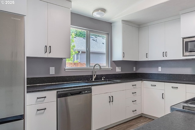 10522 SE Liebe St, Portland, OR 97266 - kitchen with appliances with stainless steel finishes, a sink, white cabinets, and dark countertops