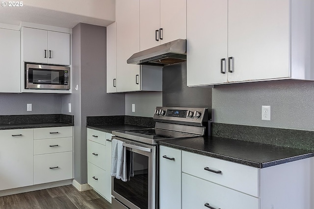 10522 SE Liebe St, Portland, OR 97266 - kitchen featuring stainless steel appliances, under cabinet range hood, dark wood finished floors, and dark countertops