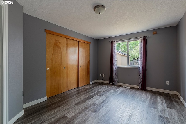 10522 SE Liebe St, Portland, OR 97266 - unfurnished bedroom with dark wood-style floors, a textured ceiling, a closet, and baseboards