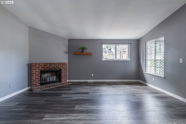 10522 SE Liebe St, Portland, OR 97266 - unfurnished living room with vaulted ceiling, dark wood-style flooring, a brick fireplace, and baseboards
