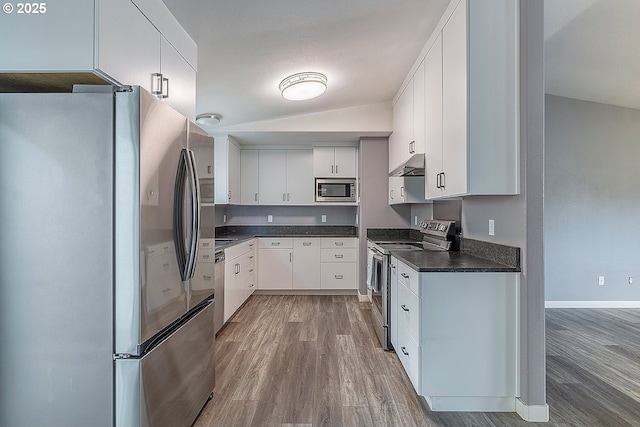 10522 SE Liebe St, Portland, OR 97266 - kitchen featuring stainless steel appliances, under cabinet range hood, wood finished floors, dark countertops, and white cabinets