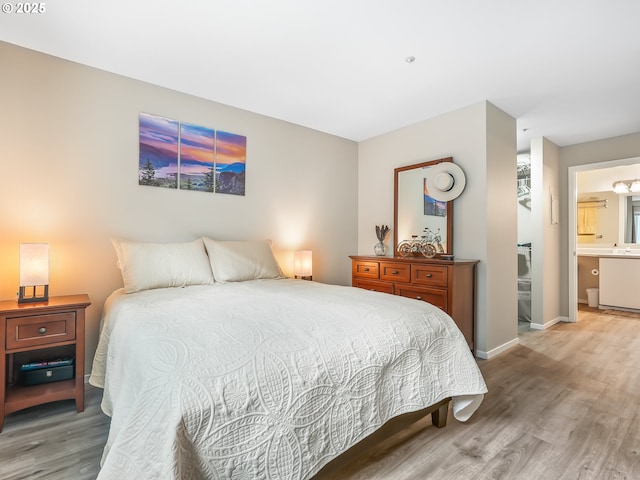 bedroom with a sink, ensuite bath, baseboards, and wood finished floors