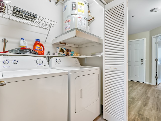 clothes washing area featuring light wood-style floors, laundry area, and washer and clothes dryer