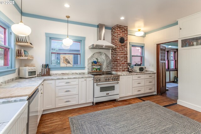 kitchen with wall chimney range hood, appliances with stainless steel finishes, plenty of natural light, white cabinetry, and crown molding